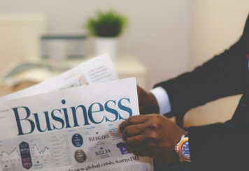 person wearing suit reading business newspaper